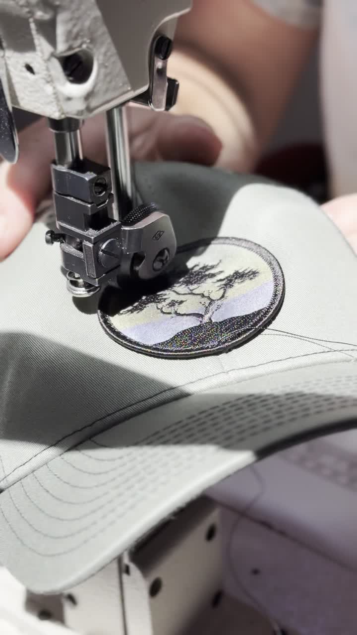 Close-up of a sewing machine stitching a patch onto a hat